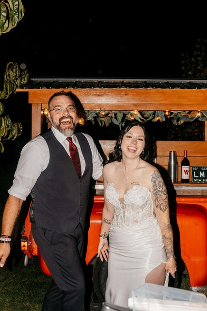 Happy wedding couple smiling in front of the 1968 Chevy tap trailer